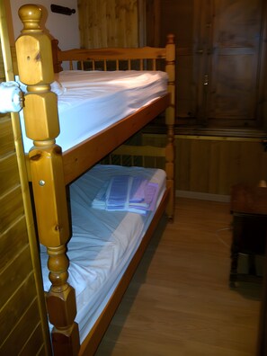 A bunk bed with wooden headboard and footboard, a wooden wardrobe, and a small table. - Casa Bohemio - Tabarca (Tabarca)