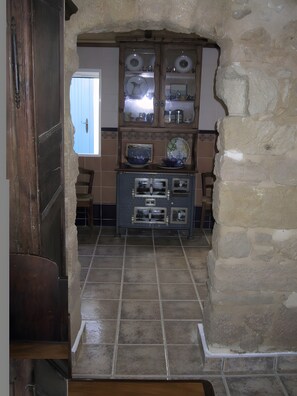 A kitchen with a stone wall, a wooden door, and a tiled floor. - Casa Bohemio - Tabarca (Tabarca)