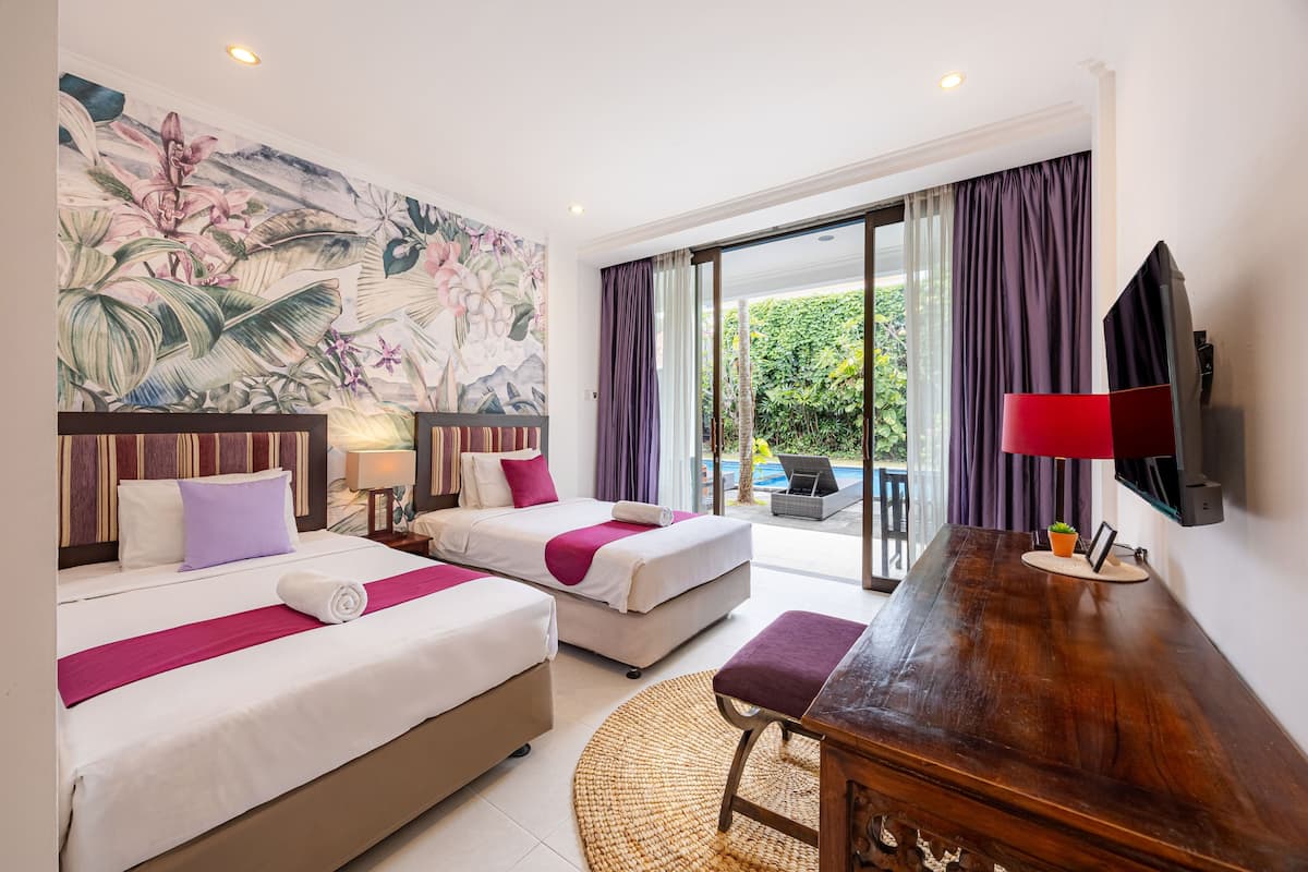 A hotel room with two beds, a wooden desk, a television, and a large mural on the wall.