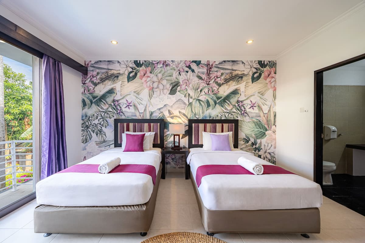 A hotel room with two beds, a balcony, and a tropical-themed mural.