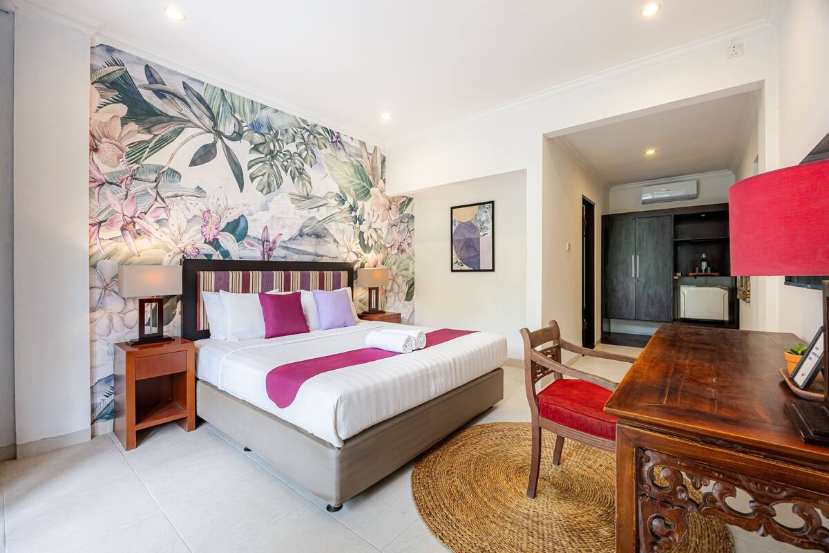 A hotel room with a bed, a nightstand, a desk, and a chair.