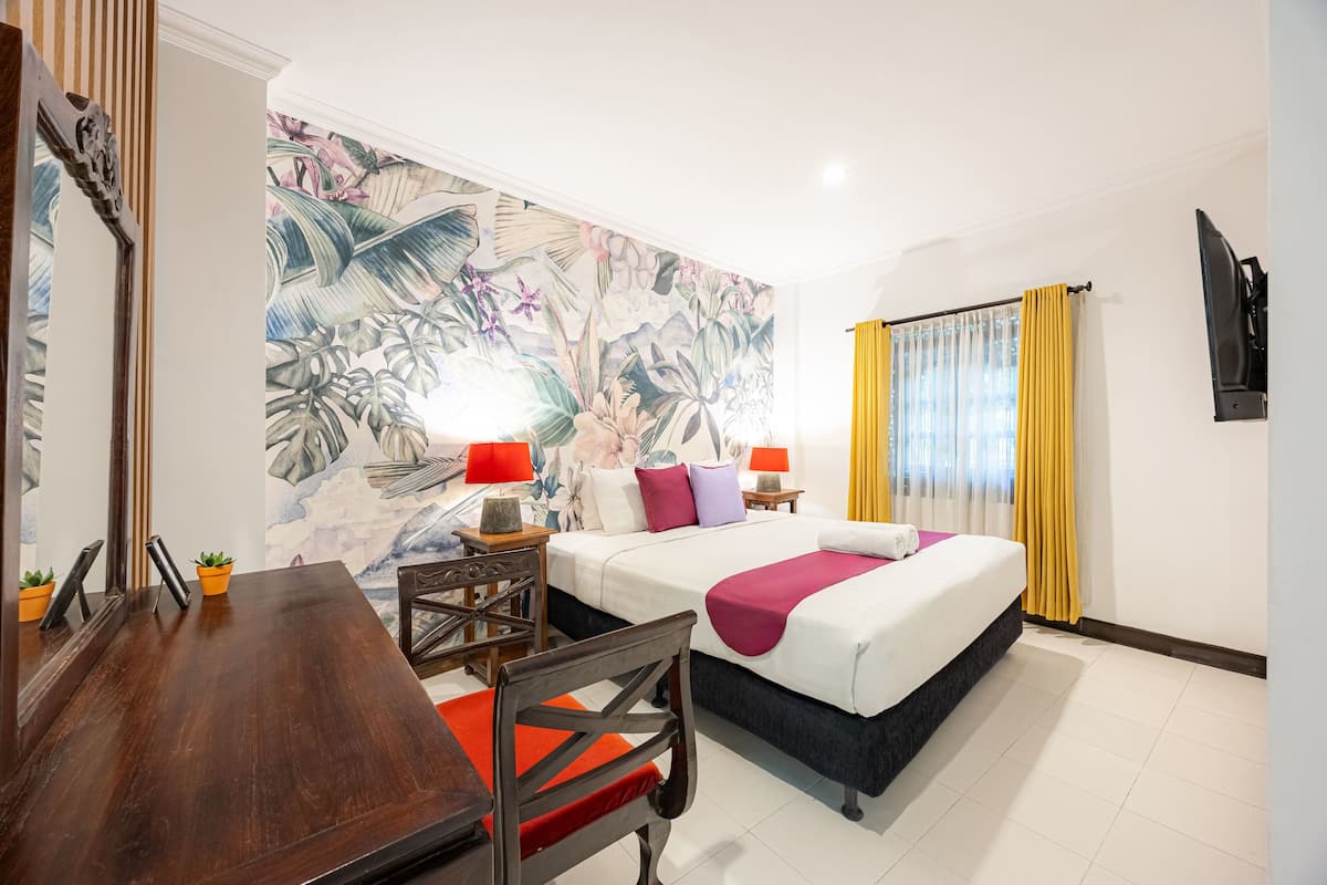 A hotel room with a bed, bedside tables, a desk, and chairs.
