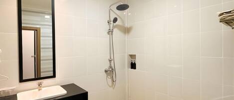 Un baño con lavabo, espejo, ducha e inodoro.