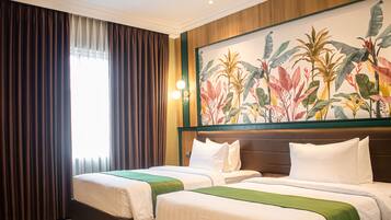 Habitación de hotel con dos camas, un gran mural tropical y vistas al exterior a través de cortinas translúcidas.