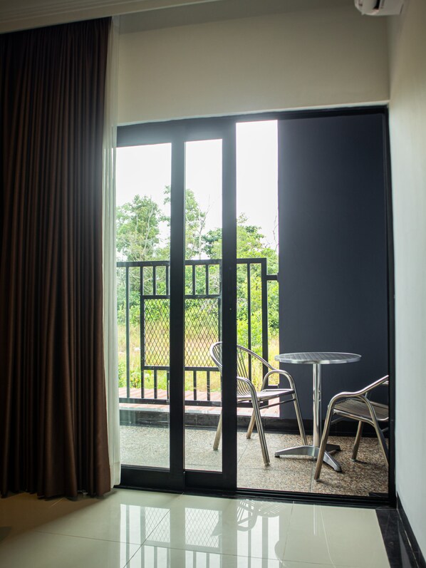 A room with a sliding glass door leading to an outdoor area with a table and chairs. - Bona Ventura Hotel & Skybar (Tanjung Pinang)