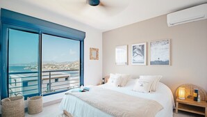 A bedroom with a large bed, a view of the sea, and a balcony. - New! Magnificent sea-view apartment in Grand Cayes - 5 min from  Pinel island (saint-martin)