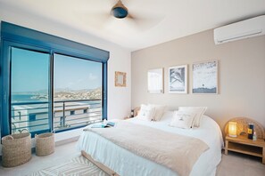 Un dormitorio con una cama grande, vistas al mar y un balcón.