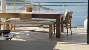 A dining area with a view of the sea, a table, chairs, and a large window. - New! Magnificent sea-view apartment in Grand Cayes - 5 min from  Pinel island (saint-martin)
