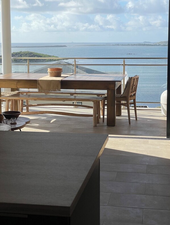 Zona pranzo con vista sul mare, un tavolo, sedie e un'ampia finestra.