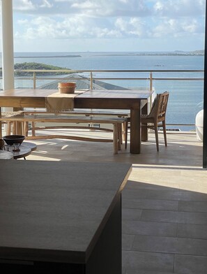 A dining area with a view of the sea, a table, chairs, and a large window.