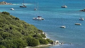 A coastal view with several sailboats anchored near a rocky shoreline. - New! Magnificent sea-view apartment in Grand Cayes - 5 min from  Pinel island (saint-martin)