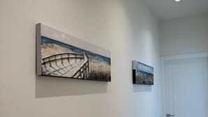Un couloir avec deux tableaux accrochés au mur, une porte et un sol carrelé.