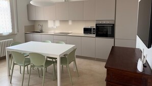 Une cuisine moderne avec une table et des chaises blanches, un four encastré et un four à micro-ondes.