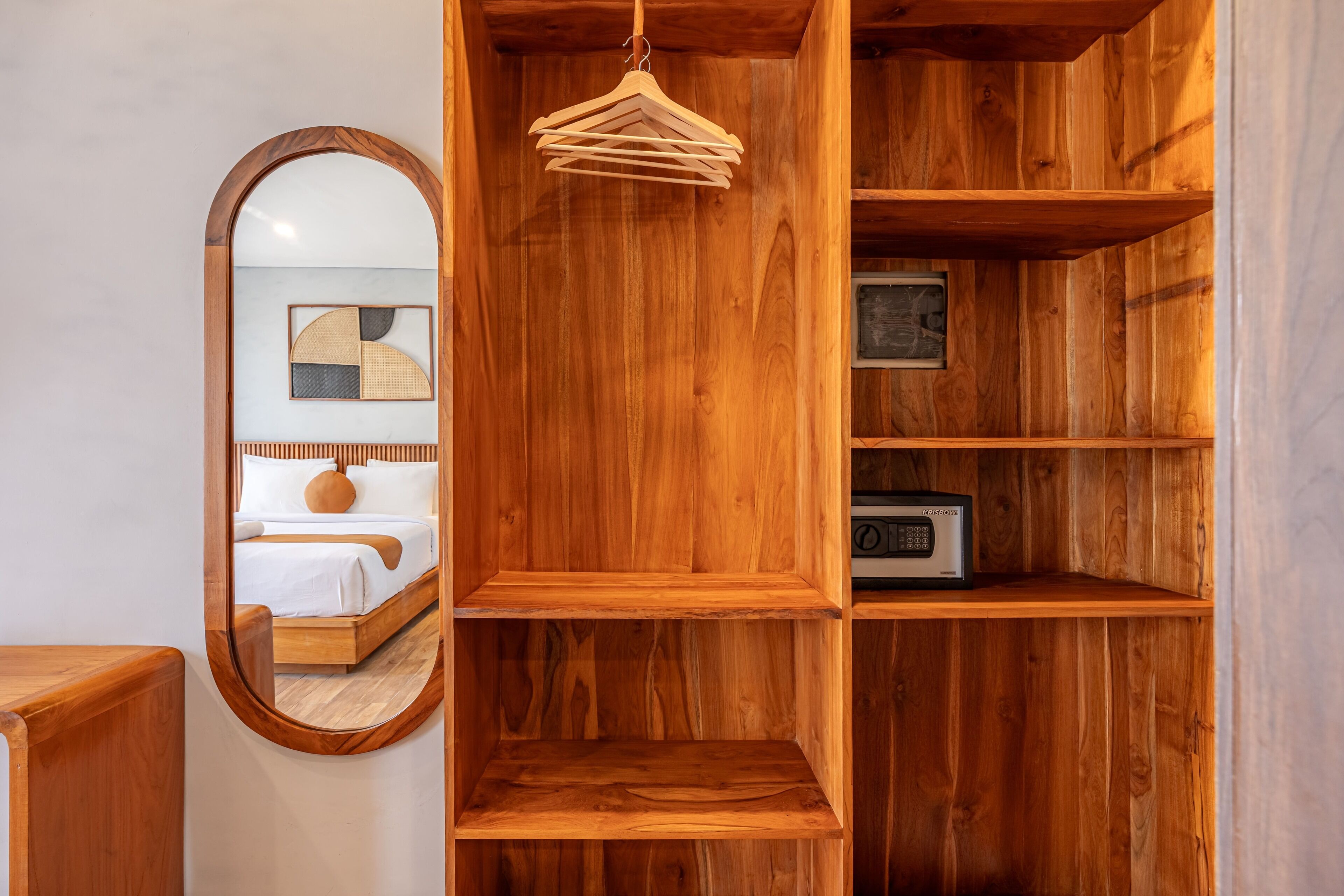 A wooden room with a bed, a mirror, and shelves with a radio.
