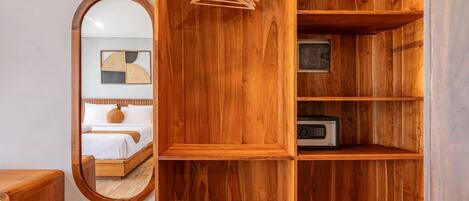 A wooden room with a bed, a mirror, and shelves with a radio.