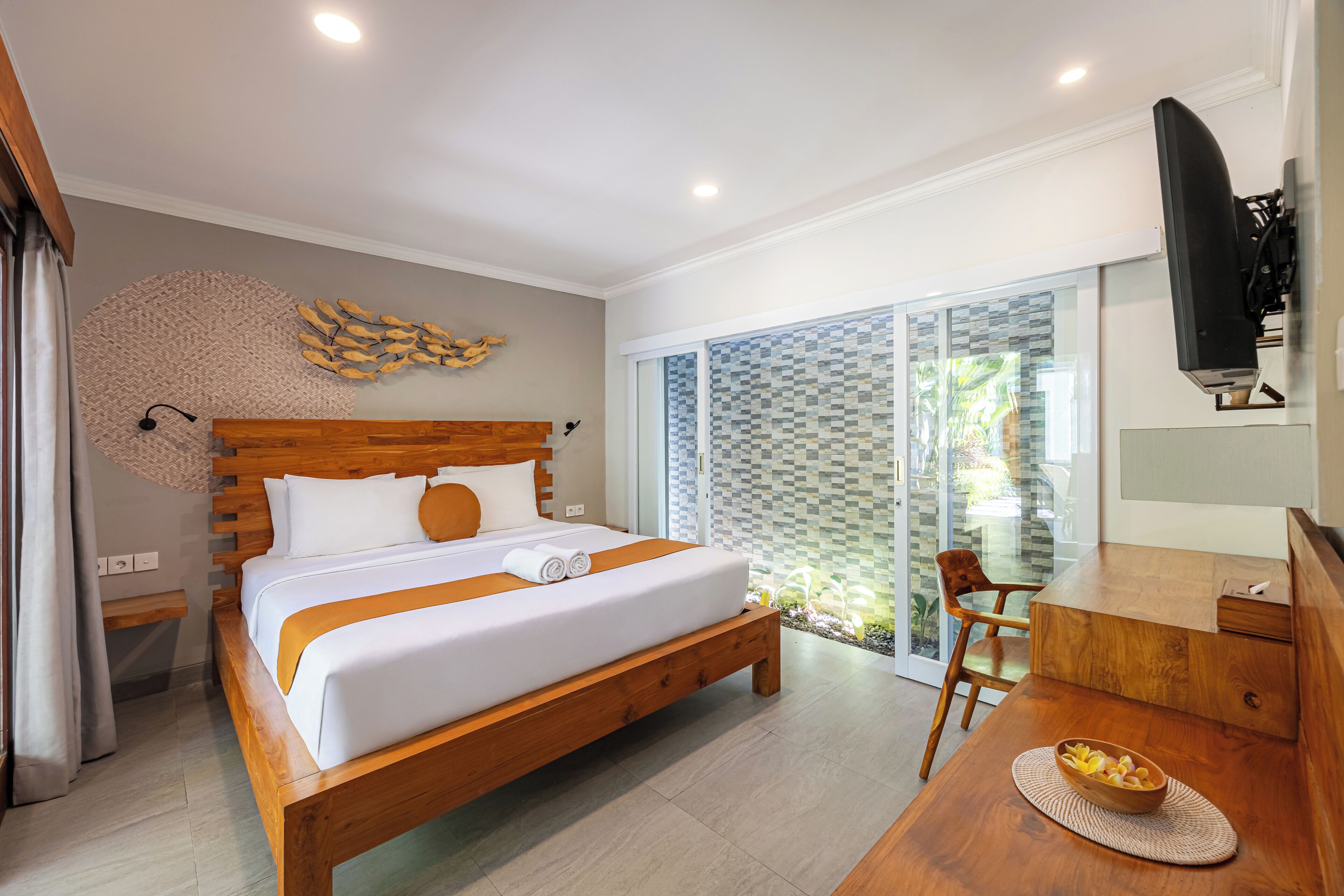 A modern hotel room with a wooden bed, a desk, and a television.