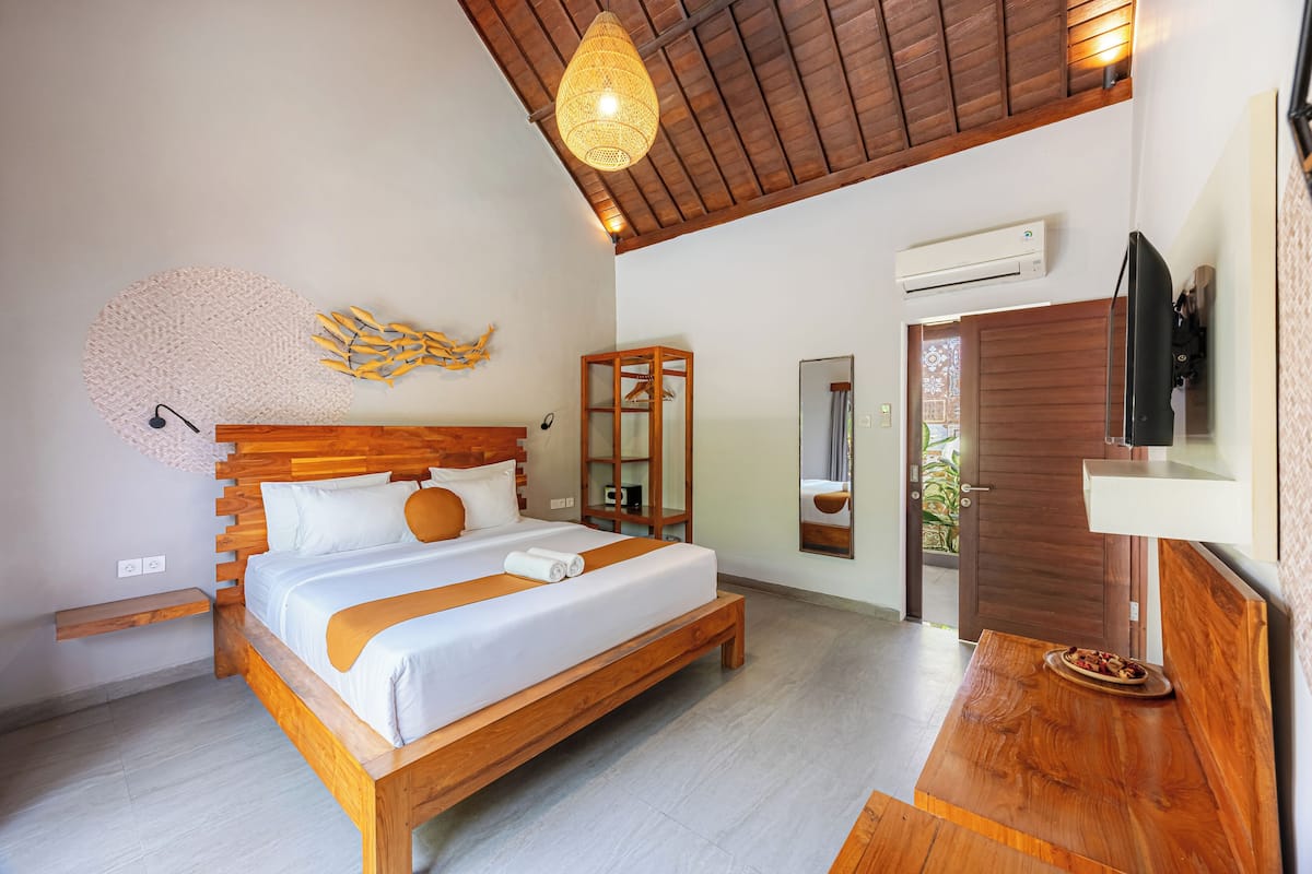 Un dormitorio moderno con una cama de madera, una lámpara colgante, un espejo y un televisor.