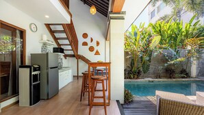 Una cocina moderna con refrigerador integrado, microondas y una mesa de madera con taburetes.
