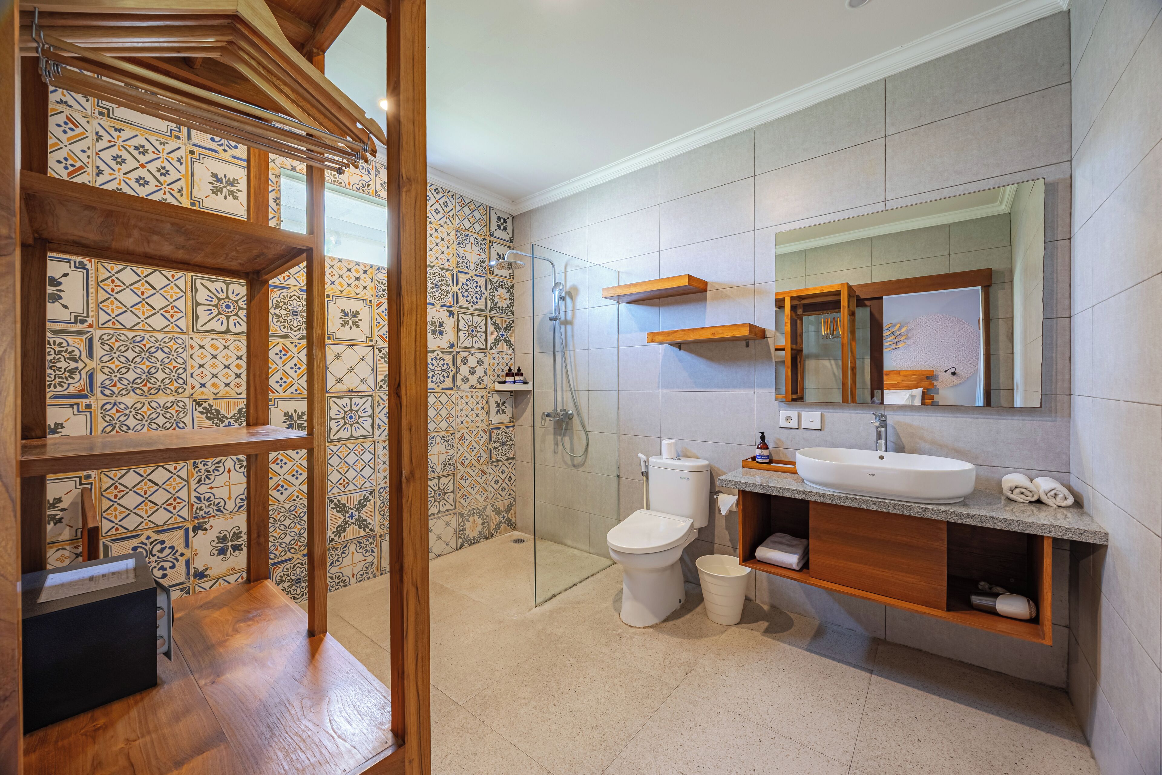 A bathroom with a tiled shower area, a toilet, a sink, and a wooden vanity.