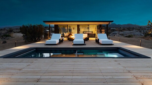 Un área de piscina exterior moderna con sillones de descanso y una terraza de madera.