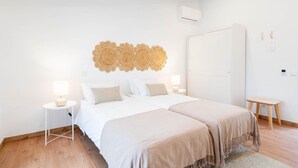 A bedroom with a bed, bedside tables, a wardrobe, and a wall-mounted air conditioner. - Room '2' with Shared Pool (Fortios)