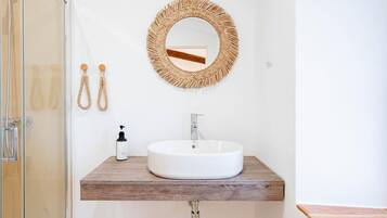 A bathroom with a round mirror, a white sink, and a wooden countertop.