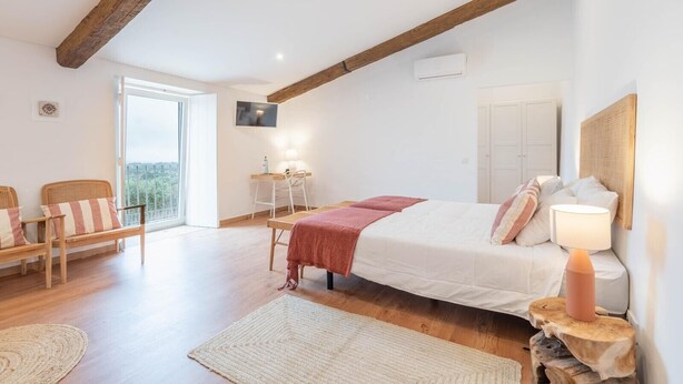 A bedroom with a bed, a desk, a chair, a lamp, and a view of the outdoors. - 'Room 3' with Shared Pool (Fortios)