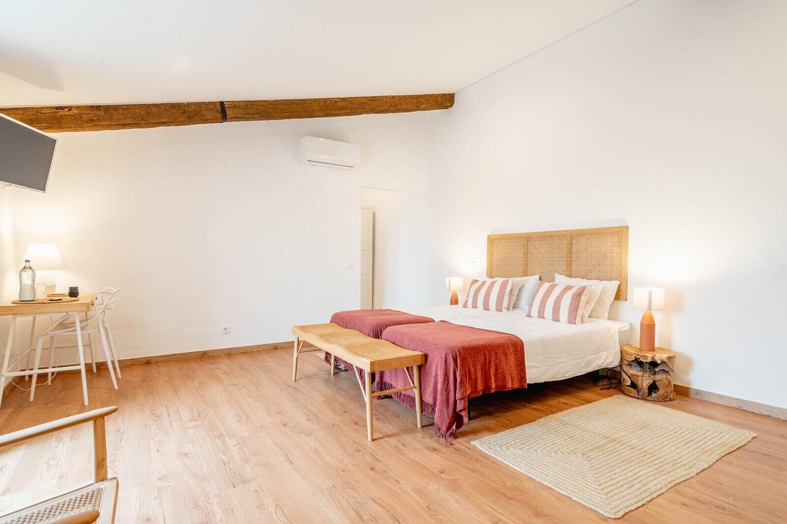 A bedroom with a bed, bedside table, lamp, and a small desk with chair.