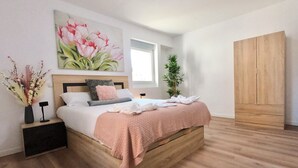 A bedroom with a wooden bed, a nightstand, a bedside table, a window, a wardrobe, and a painting on the wall. - Oshun Valdecanillas (Madrid)