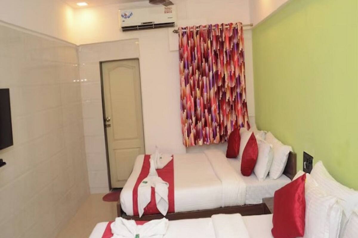 Habitación de hotel con cama, ventilador de techo, aire acondicionado y cortina colorida.