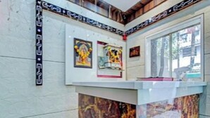 Eine Rezeption mit einer Marmor-Theke, gerahmten Kunstwerken an der Wand und einem Fenster mit Blick ins Freie.