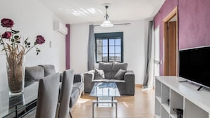 A modern living room with a sofa, a glass coffee table, and a TV stand. - Apartment 50 Meters from the Beach with Terrace and Sea Views (Conil de la Frontera)
