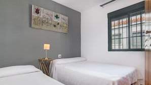 A room with two beds, a wall-mounted lamp, and a window with a view. - Apartment 50 Meters from the Beach with Terrace and Sea Views (Conil de la Frontera)