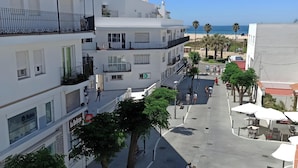 A multi-story building with balconies, a paved street, and a beach in the background. - Apartment 50 Meters from the Beach with Terrace and Sea Views (Conil de la Frontera)