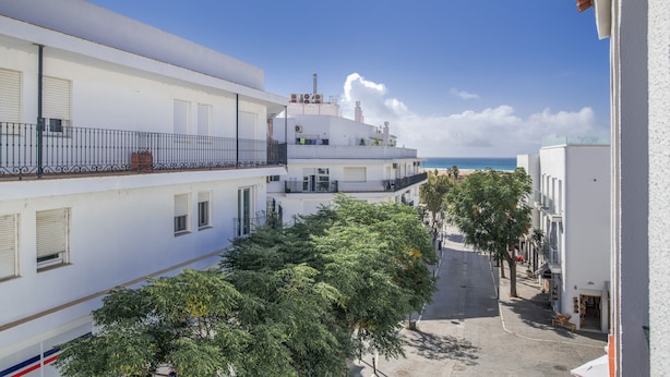 A multi-story building with balconies, a paved street, and a clear sky. - Apartment 50 Meters from the Beach with Terrace and Sea Views (Conil de la Frontera)
