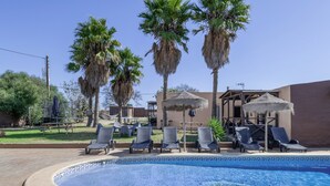 Una piscina con sillas de descanso y palmeras.