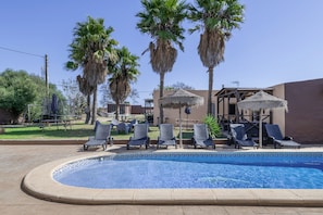 A swimming pool with lounge chairs and palm trees.