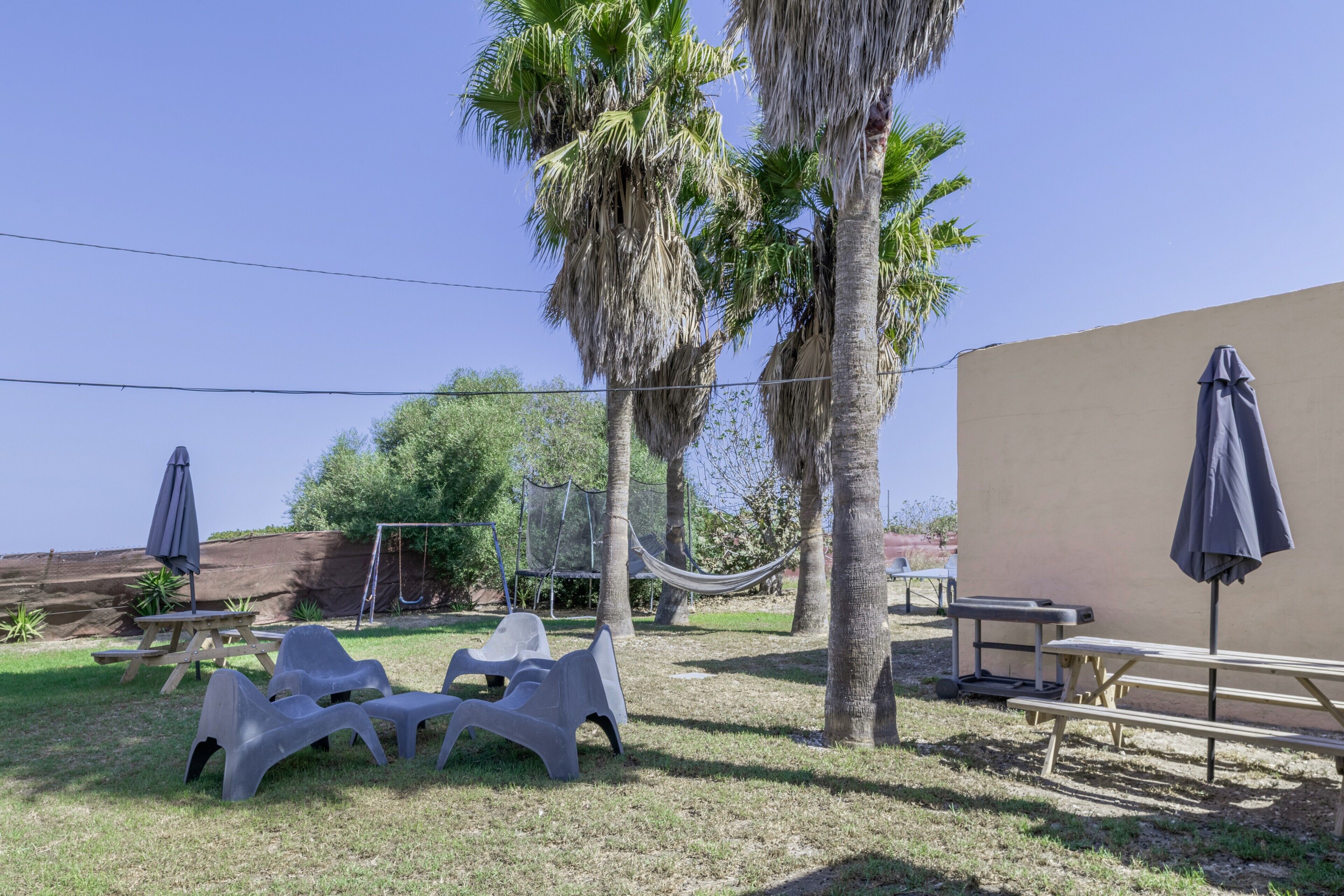 A patio area with plastic chairs, a table, and a hammock.