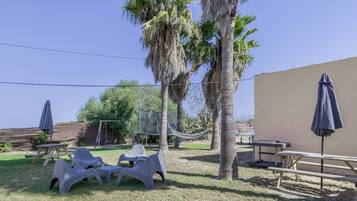 A patio area with plastic chairs, a table, and a hammock.