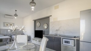 Una cocina moderna con una mesa de comedor de vidrio, sillas blancas, un microondas integrado y un refrigerador.