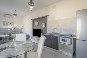 A modern kitchen with a glass dining table, white chairs, a built-in microwave, and a refrigerator.
