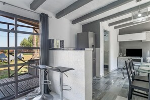 Une cuisine moderne avec un coin bar, une table à manger et un téléviseur.