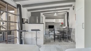 Quarto de hotel moderno com cama, escrivaninha, cadeira, mesa de jantar e cozinha.