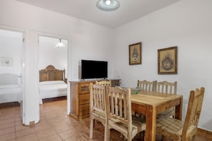 Une chambre avec un lit, une télévision, des meubles en bois et deux tableaux encadrés au mur.