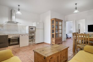 Une cuisine spacieuse avec un coin repas, des meubles en bois et un sol carrelé.