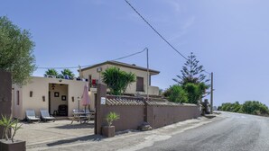 Un edificio residenziale con patio, area salotto esterna e un piccolo giardino.