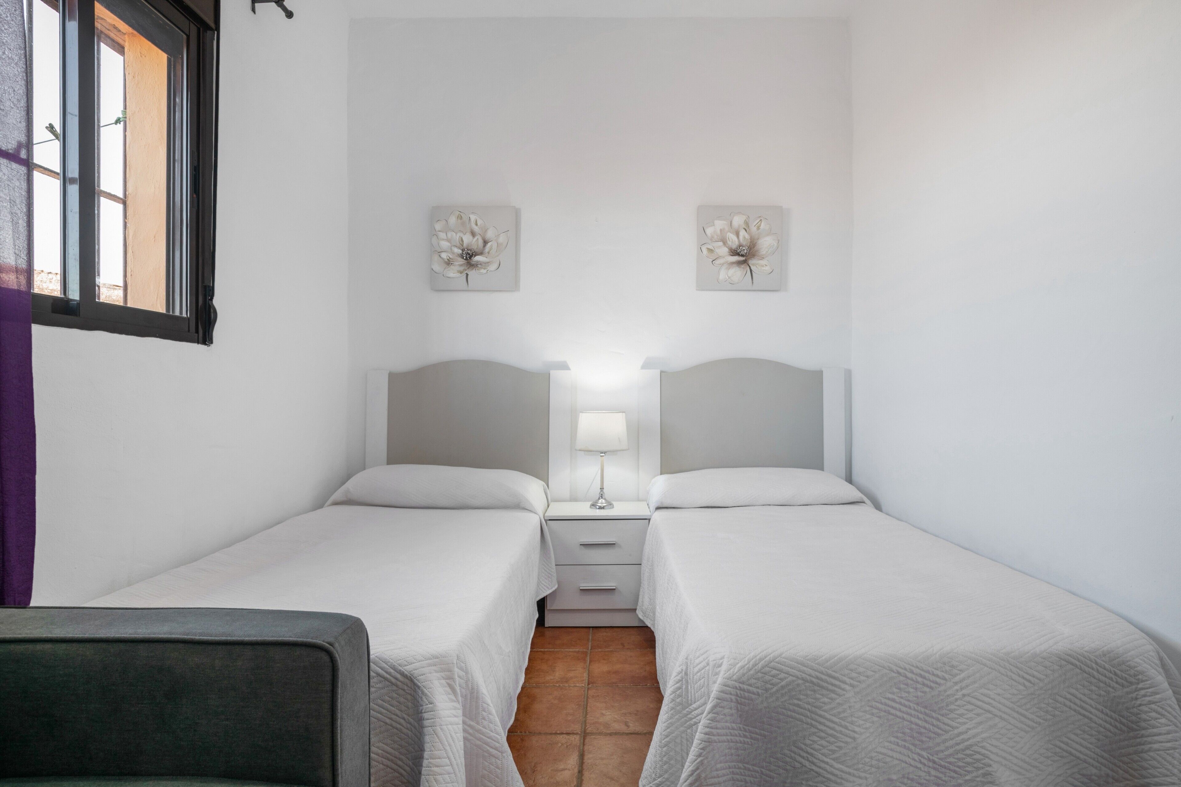 Ein Doppelzimmer mit zwei Betten, einem Nachttisch mit Lampe und einem Fenster mit Blick.