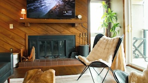 A living room with a fireplace, a television mounted above it, and a comfortable seating area with a chair and ottoman. - Ledges   66 with Wintergreen Advantage (Wintergreen)