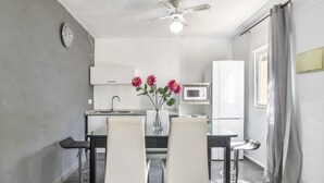 Eine moderne Küche mit Essbereich, weißen Schränken, einer Mikrowelle und einem Deckenventilator.