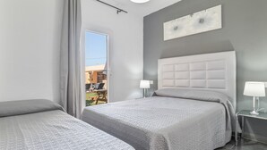 Ein Hotelzimmer mit zwei Betten, einem großen Fenster, einem modernen Kopfteil und Blick ins Freie.